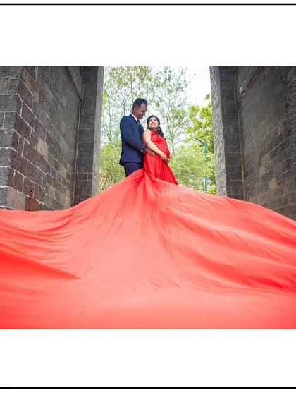 A dramatic, wide-angle shot of a couple framed by a massive, flowing red gown.