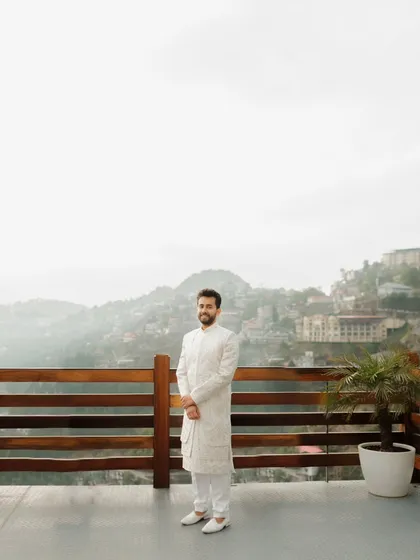 A portrait of the groom standing on a balcony overlooking the hills of Mussoorie. It's a moment of quiet anticipation before the ceremony.