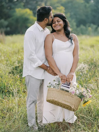A sweet outdoor portrait incorporating a basket of flowers and their ultrasound scan. It’s a lovely way to combine romantic elements with the personal story of their pregnancy.