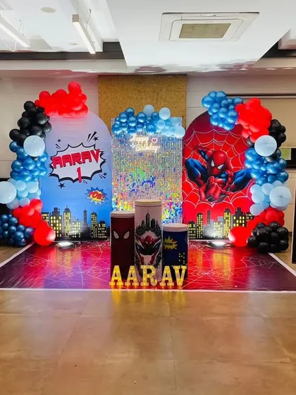 A full-blown Spiderman and Avengers-themed birthday for Aarav. The backdrop features a city skyline, Spiderman graphics, and balloon arches in the hero's signature red and blue colors.