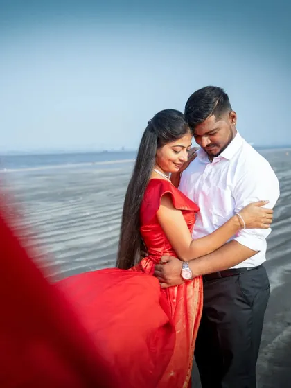 A romantic embrace on the beach, with the bride's red dress flowing in the wind. A classic, cinematic pre-wedding shot.