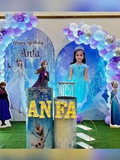 A personalized Frozen-themed stage setup for Anfa's 6th birthday, complete with a custom backdrop, marquee number, and character props.