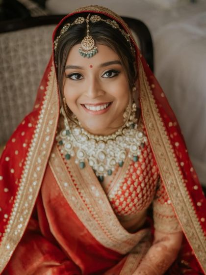 This close-up captures the joy and confidence of a bride on her wedding day. The makeup is classic and clean, with defined eyes and a natural lip that enhances her beautiful smile.