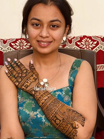 A graceful back-of-hand design featuring a peacock at the wrist and traditional motifs on the hand. The details are fine and elegant, perfect for a sophisticated bridal look.