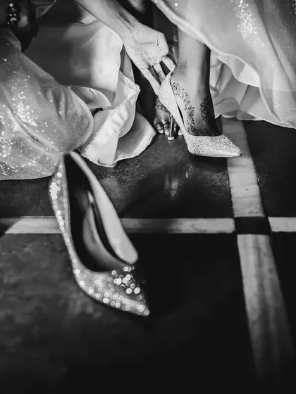 A detail shot in black and white, showing the bride changing her shoes. It's a real, unscripted moment that's part of the complete wedding story.
