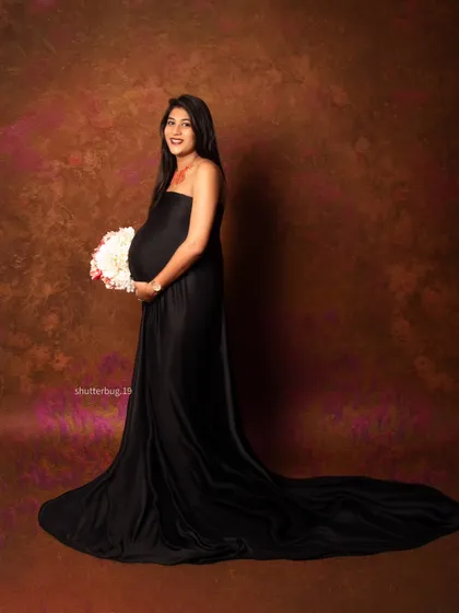 A beautiful solo portrait where the mom-to-be holds a bouquet of flowers. The contrast between the soft flowers and the bold black gown creates a visually stunning and elegant image.