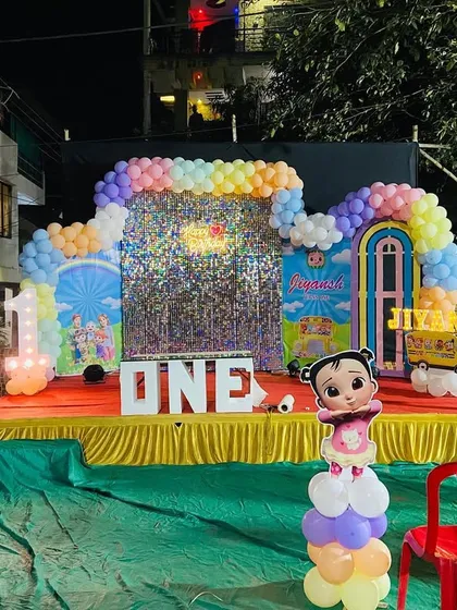 Another angle of the Cocomelon birthday stage, showing the full balloon arch over the shimmer backdrop and the arrangement of character props.