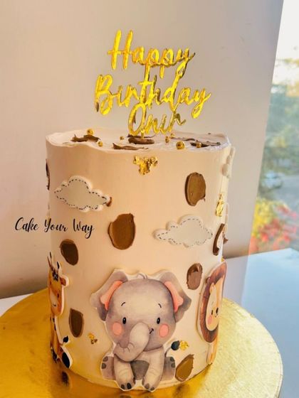 A wildly cute and tall jungle animal cake, featuring a baby elephant and giraffe.
