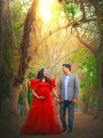 A romantic walk through a tree-lined path. The vibrant red tulle gown stands out beautifully against the natural greenery, creating a storybook feel.