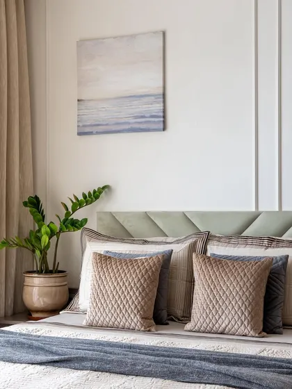 The parents' bedroom in our 'EcoChic Abode' project. The calming palette of neutrals, beiges, and a pista green headboard creates a serene and harmonious environment.