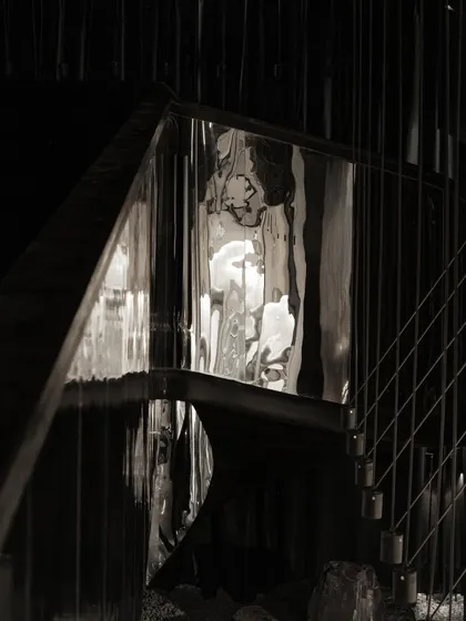 A detail of the staircase's reflective surface, capturing distorted images of the space.