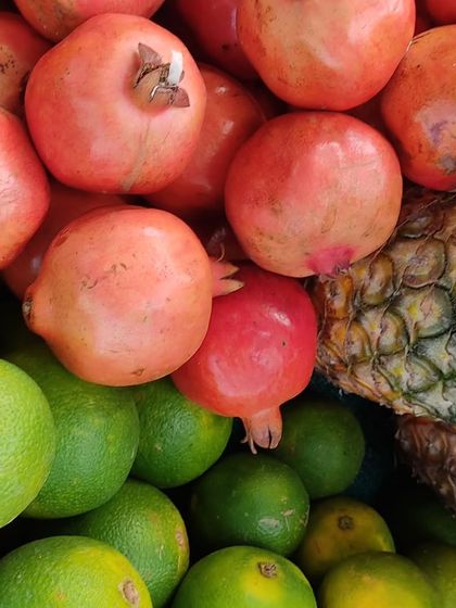 A close-up of fresh pomegranates, sweet limes, and a pineapple, showing the variety of fruits available.