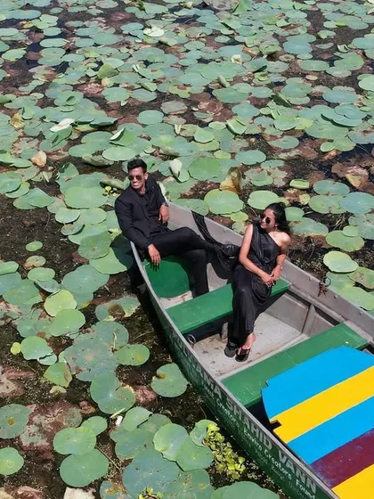An epic drone shot from a serene pre-wedding shoot on a lake filled with lily pads. This aerial perspective shows the grand scale of the location and the quiet intimacy of the couple, creating a stunning visual contrast.