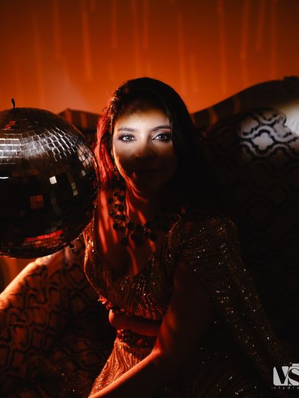 A creative and moody portrait of Archana with a disco ball. The dramatic shadows and the single light source on her face create a mysterious and glamorous look, perfect for a sangeet night.