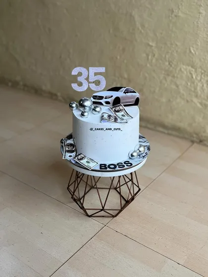 For the boss who loves cars. This Mercedes-themed cake is decorated with an edible car image, the number 35, and money accents.