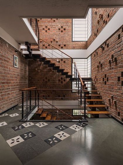 This staircase in Roopasri's home is set against a feature wall of exposed rat-trap bond brickwork. The design is not just functional but also a beautiful display of sustainable building techniques and material texture.