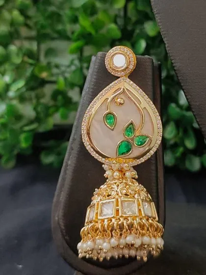 The matching jhumka earring, featuring the same elegant painted leaf motif, designed to complete this distinctive bridal look.