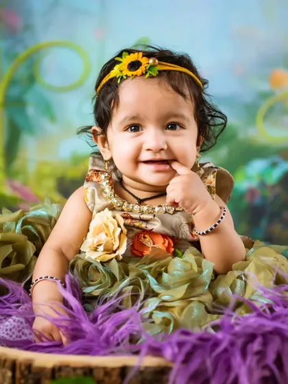 A sweet and curious expression from a baby girl in a beautiful floral dress. This is a classic example of a sitter session portrait.