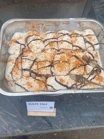Kulfi Idli, a creative fusion dessert appetizer, drizzled with chocolate sauce and spices for a surprising twist.