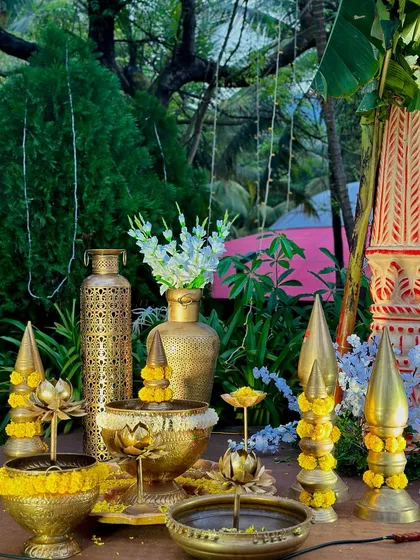 A collection of beautiful brass props, including vases and lotus-themed diyas, ready to be placed at an event. The beauty of an event truly lies in the details.
