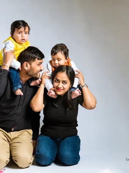 A fun and playful family portrait with twin toddlers. Having the boys on their parents' shoulders creates a dynamic and joyful image that is full of life and personality.