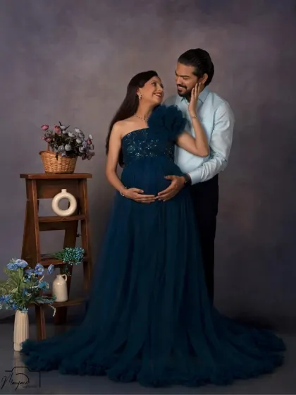 A beautiful couple's portrait in a deep teal gown. The simple background and props keep the focus on their loving interaction.