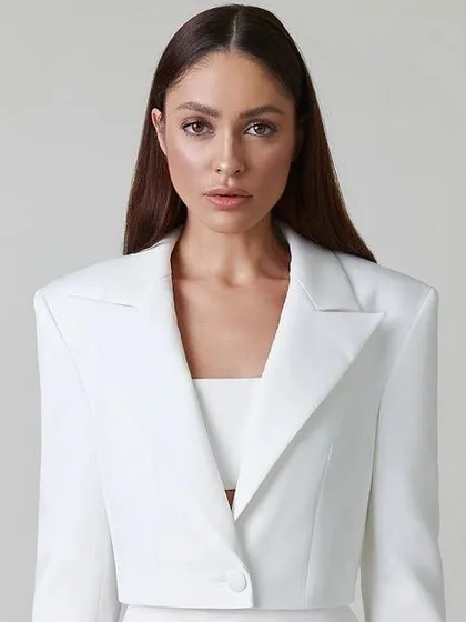 A close-up of a white cropped blazer, a versatile piece that can be part of a suit or styled separately.