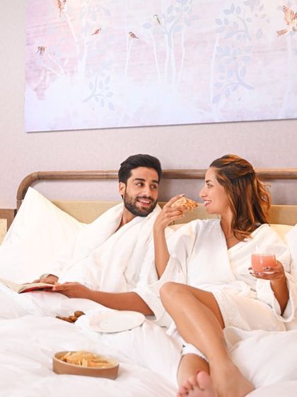 Romance and relaxation go hand in hand. A couple enjoys breakfast in bed in one of our luxurious rooms, a perfect start to a day of connection and indulgence.