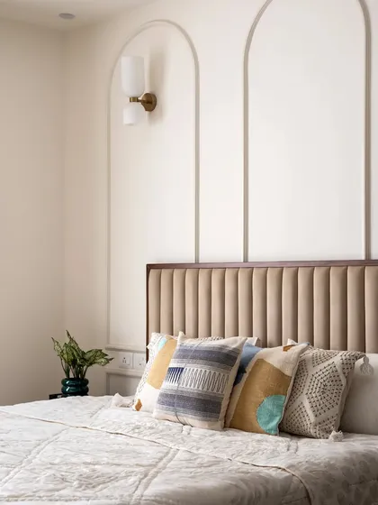 The master bedroom features a beautiful curved wall beading highlight, complemented by a scone wall light. The headboard, a combination of fabric and veneer, adds a luxurious feel.