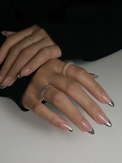 A modern take on a timeless classic. This set features long, almond-shaped nails with a flawless nude base and striking silver chrome French tips for a sleek, futuristic look.