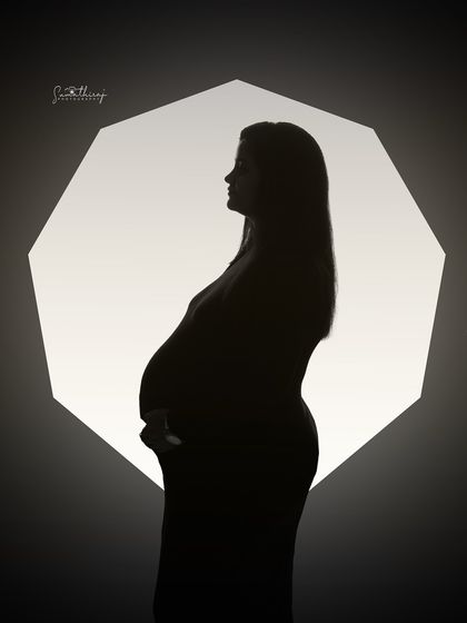 A striking silhouette against a geometric octagon of light. This artistic and modern shot creates a unique and memorable portrait of the mother-to-be.