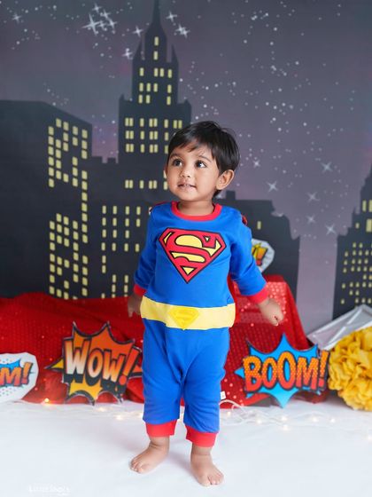 It's a bird, it's a plane, it's Super Baby! This little hero is ready to save the day in front of a cityscape backdrop, making for a powerful and adorable superhero portrait.