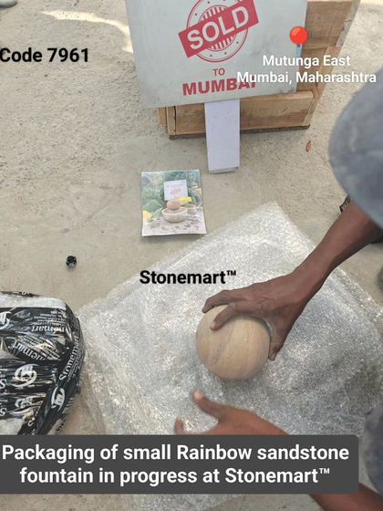 Before packing, we ensure every piece is perfect. Here, our artisan inspects a small rainbow sandstone sphere before it's bubble-wrapped.