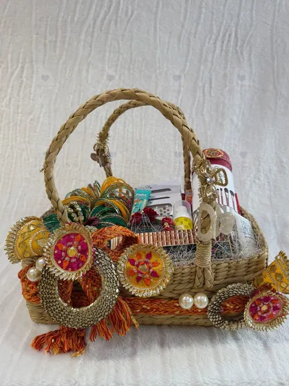 A charming and traditional Diwali gift basket. This woven basket is decorated with colorful 'gota' rings and filled with an assortment of small gifts and essentials.