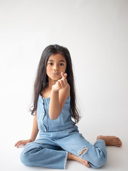 A cute and modern pose, making a heart symbol with her fingers. It's these little details that show who they are at this age.