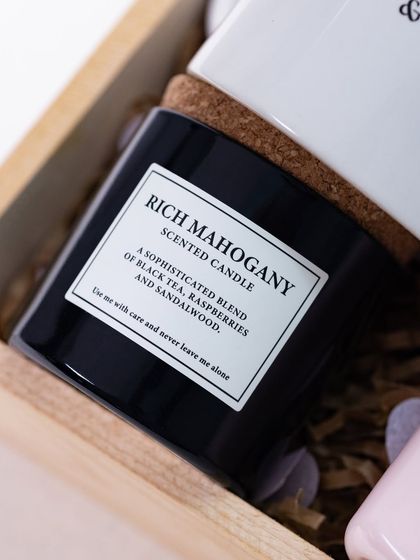 A 'Rich Mahogany' scented candle adds a touch of sophisticated fragrance and ambiance to the newlywed gift hamper.