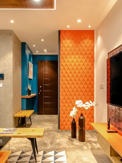 A bright orange 3D-paneled wall creates a bold point of emphasis in this living room, adding texture and vibrant color.