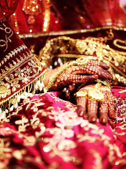 A soft, romantic shot of the bride's hands, with the focus on her intricate jewelry and the beautiful henna stain.