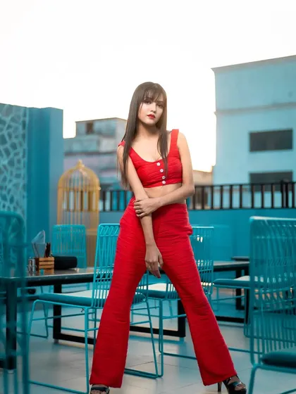 A full-length shot from a rooftop location, showcasing the complete western-style outfit and the bold makeup that complements it.