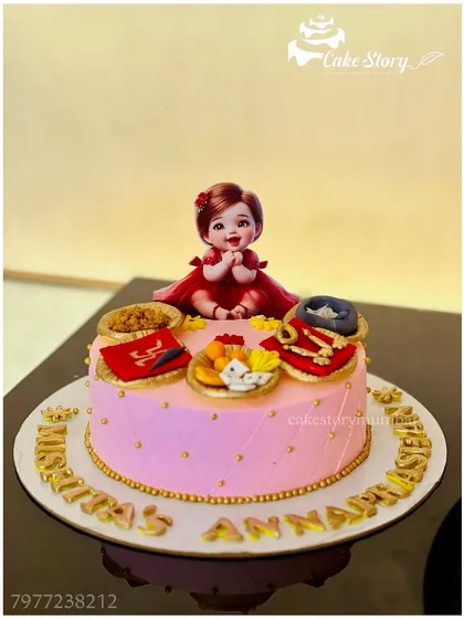 A beautiful cake for an 'Annaprashan' ceremony, celebrating a baby's first taste of solid food. The design includes traditional elements and a cute baby topper.