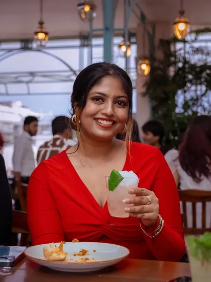 A guest in red, enjoying a light and refreshing cocktail and the lively atmosphere.