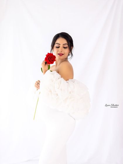 A close-up to capture that beautiful pregnancy glow. The soft fabric of the white gown and the delicate touch of the rose add a touch of timeless romance to this maternity portrait.