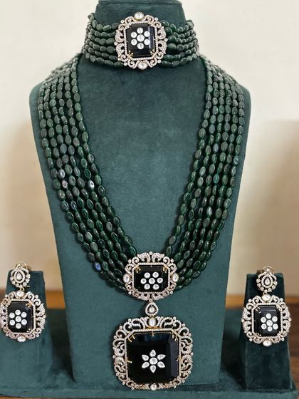 A unique bridal set with black stones and American diamond floral motifs. This rental set includes a choker, a long multi-strand necklace, and matching earrings.