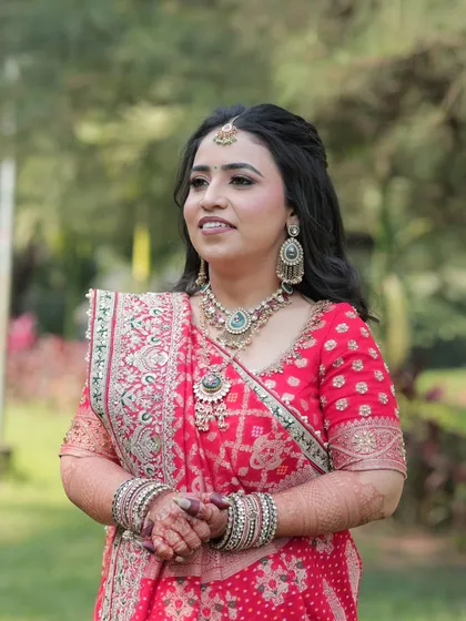 A candid moment of the bride during her engagement ceremony, looking radiant in her red and gold attire.
