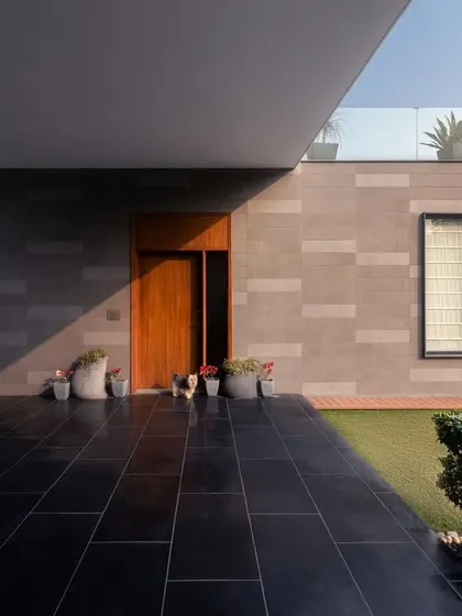 The entrance to the KKB Residence showcases our use of natural stone cladding and a cantilevered roof, creating a powerful and welcoming first impression. The contrast between the dark stone floor and the lighter wall panels adds depth and texture.