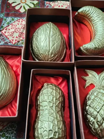 A variety of my fruit and nut-shaped urli candles, including coconut, banana, peanut, and pineapple, packed in satin-lined gift boxes.