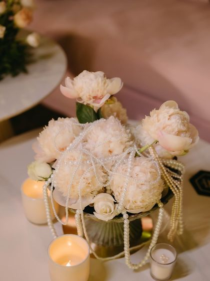 A centerpiece of white peonies draped with strings of pearls, a simple yet incredibly elegant and romantic detail.