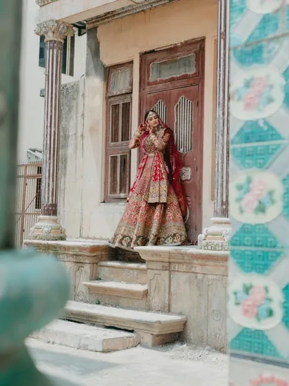 A wide-angle shot capturing the bride's magnificent lehenga and the old-world charm of the location.