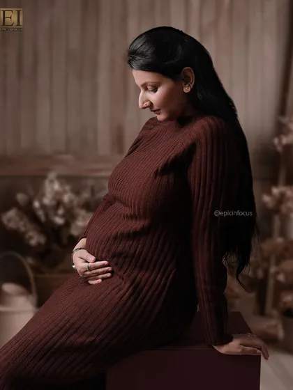 A side profile in the comfortable brown knit dress, capturing a quiet moment of connection with the baby.