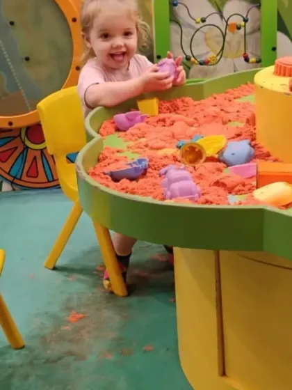 The joy of sensory play is clear on this little girl's face as she plays with kinetic sand.